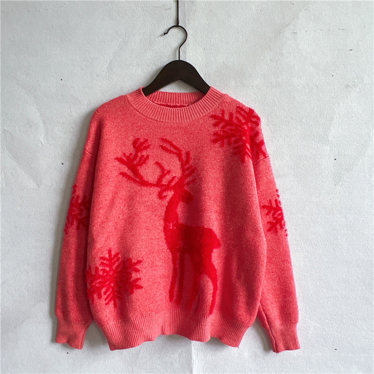 Cozy red knit sweater with reindeer and snowflake accents, ideal for staying warm during the holiday season.

