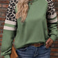 Close-up of a trendy sage green sweatshirt featuring leopard print and contrast stripes.
