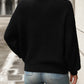 Back view of relaxed fit black textured knit sweater on woman outdoors
