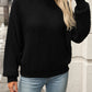 Woman wearing cozy textured knit mock neck sweater in black with jeans
