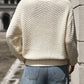 Back view of relaxed fit cream textured knit sweater on woman outdoors
