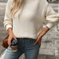 Woman wearing cozy textured knit mock neck sweater in cream with jeans
