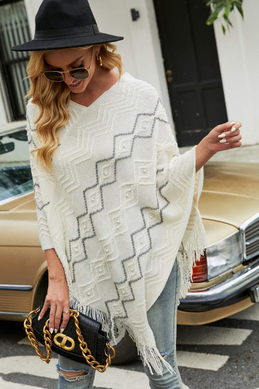 Soft white poncho with pearl detailing and fringe hem
