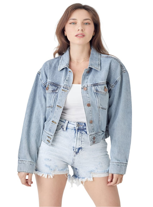 Woman wearing a cropped denim jacket styled with high-waisted shorts.
