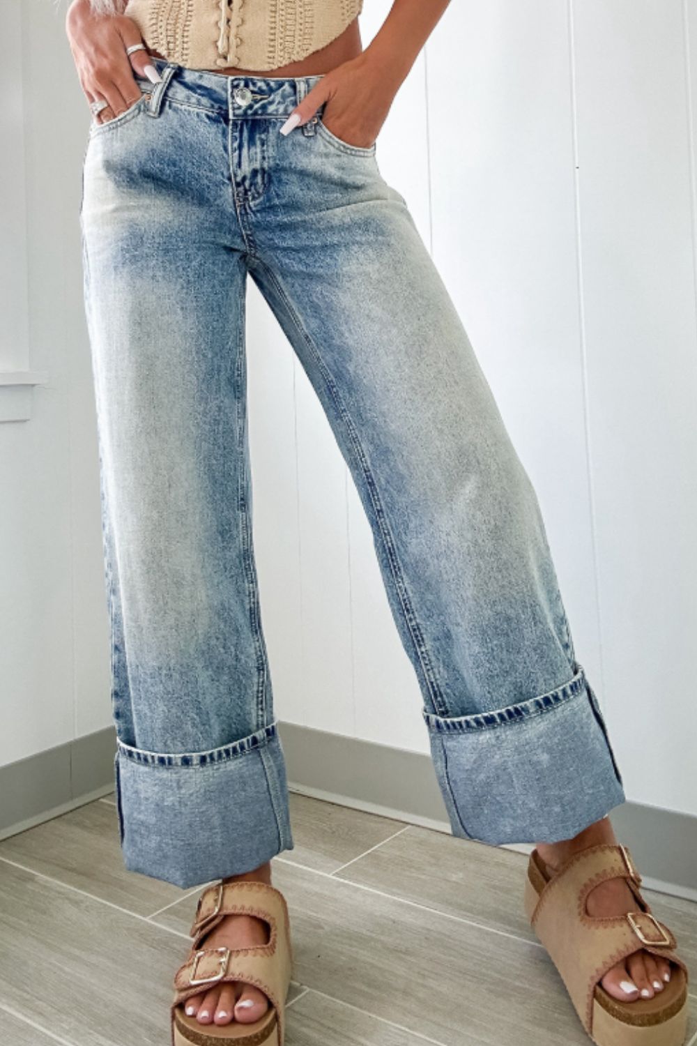 Functional pocket detail on cuffed light wash wide leg jeans for practicality.
