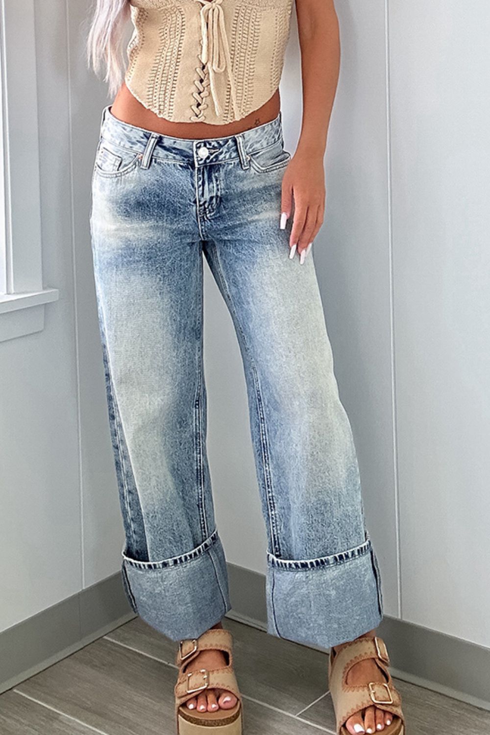 Cuffed light wash wide leg jeans styled with wedges for a casual-chic outfit.
