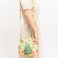 Floral patterned bucket bag with green tassels.