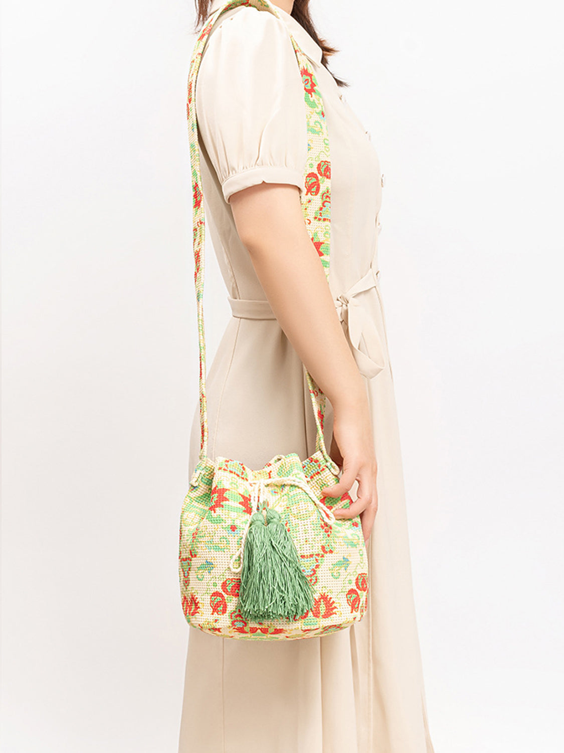 Floral patterned bucket bag with green tassels.