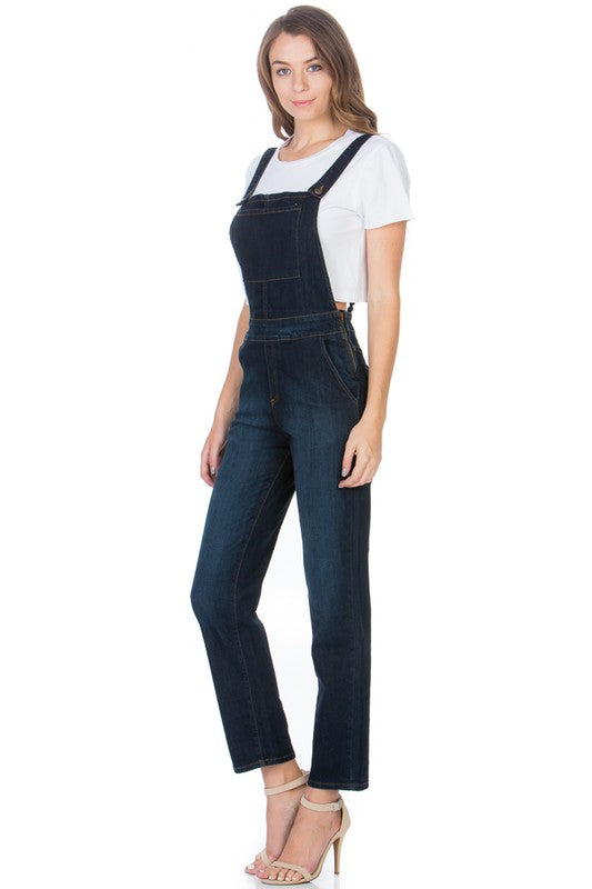 Side view of dark wash denim overalls featuring utility and side pockets.
