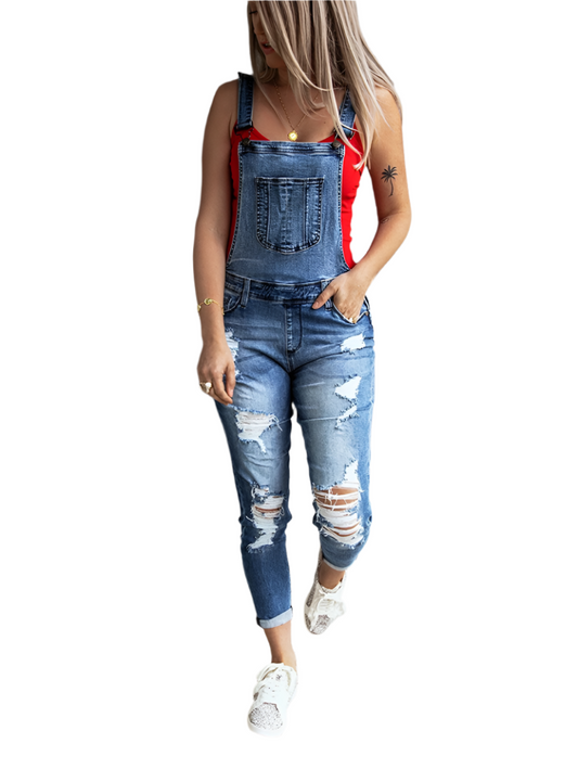 Woman wearing distressed denim overalls with adjustable straps.
