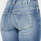 Back view of wide waistband flare jeans with subtle distressing and raw hem.
