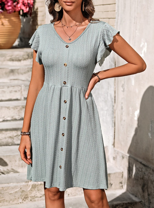 Elegant V-neck dress with playful ruffles and decorative buttons, perfect for any occasion. Available in six colors for a versatile wardrobe.