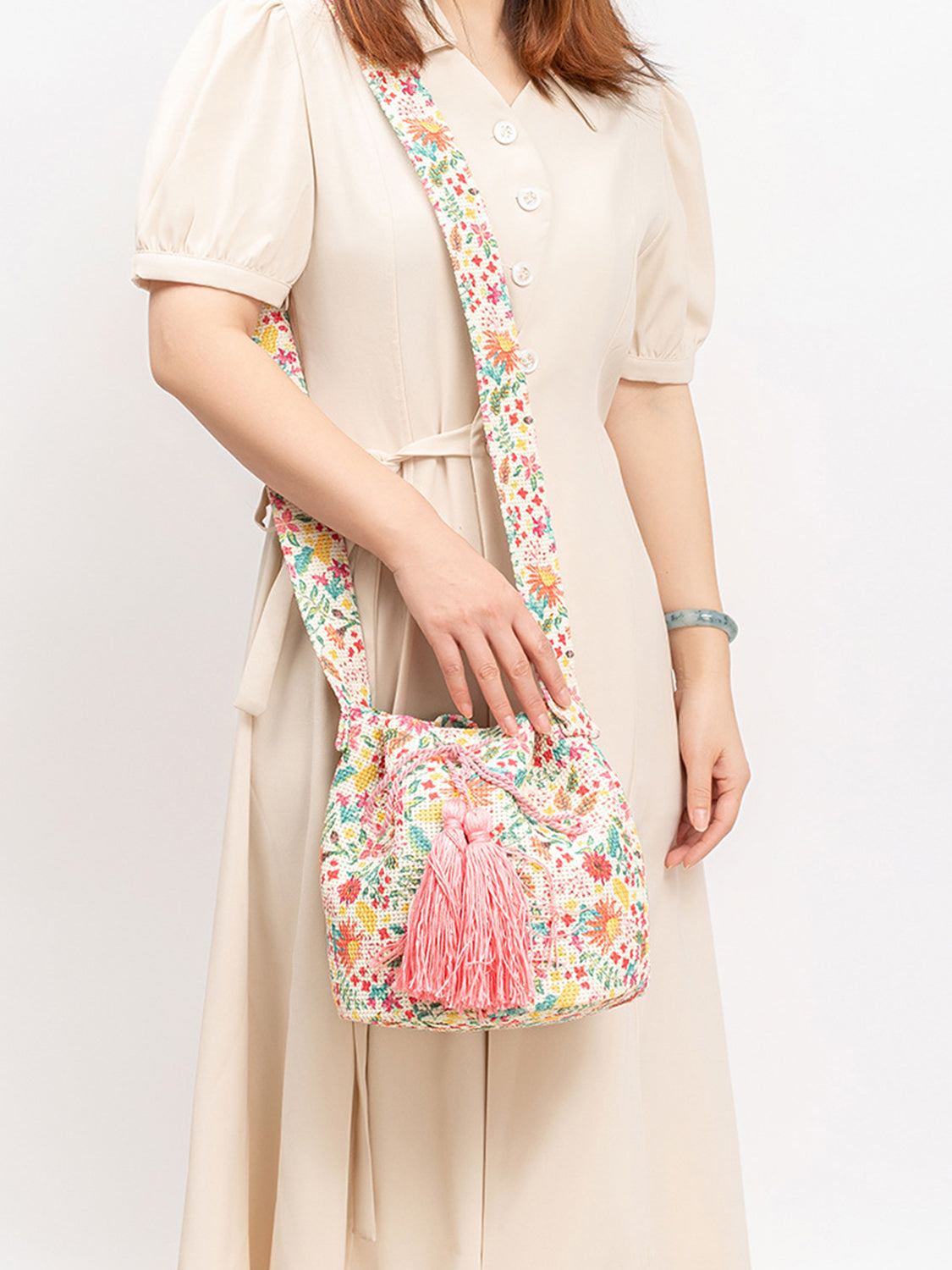 Pink tassel bucket bag with intricate floral patterns.