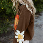 Close-up of brown sweater featuring vibrant flower designs and a V-neck | boho aesthetic
