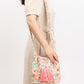 Floral patterned bucket bag with vibrant pink tassels.