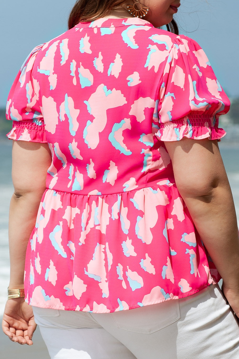 Woman in a flowy pink camo top with ruffle sleeves