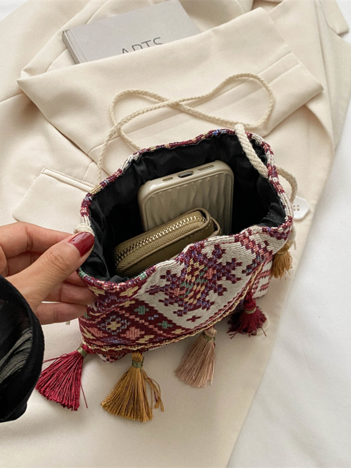 Colorful geometric patterned drawstring pouch with tassel accents in wine.