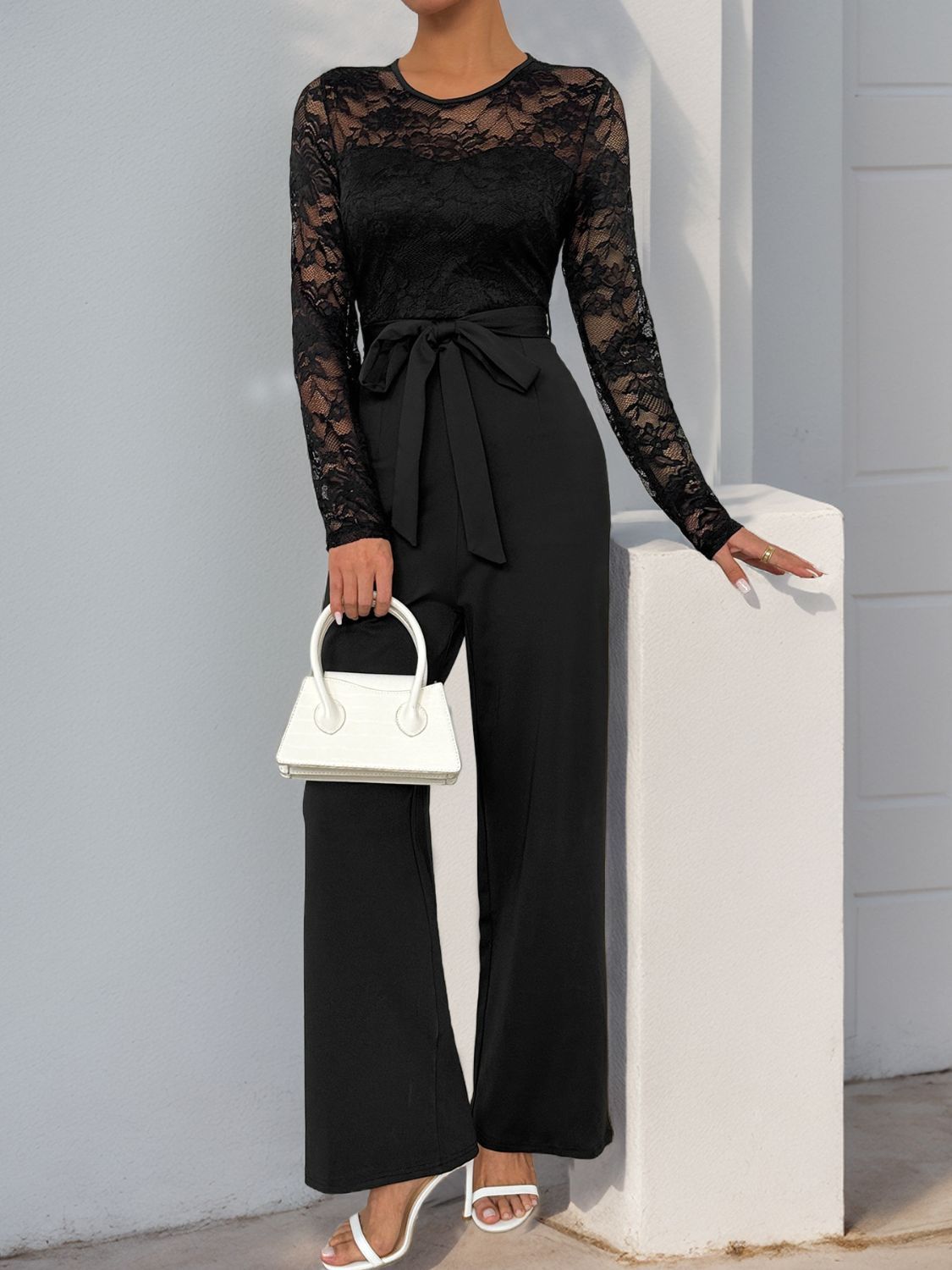 Close-up of the lace top and waist tie of black jumpsuit.
