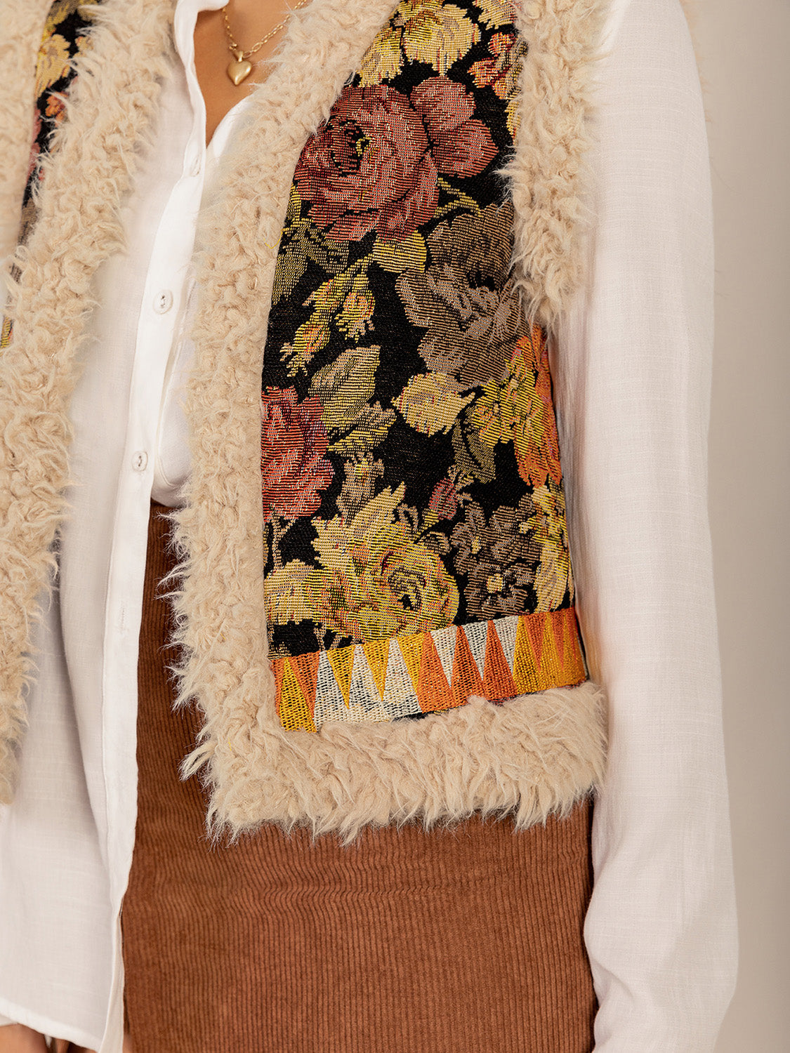 Close-up of faux shearling trim and floral embroidery on boho vest.
