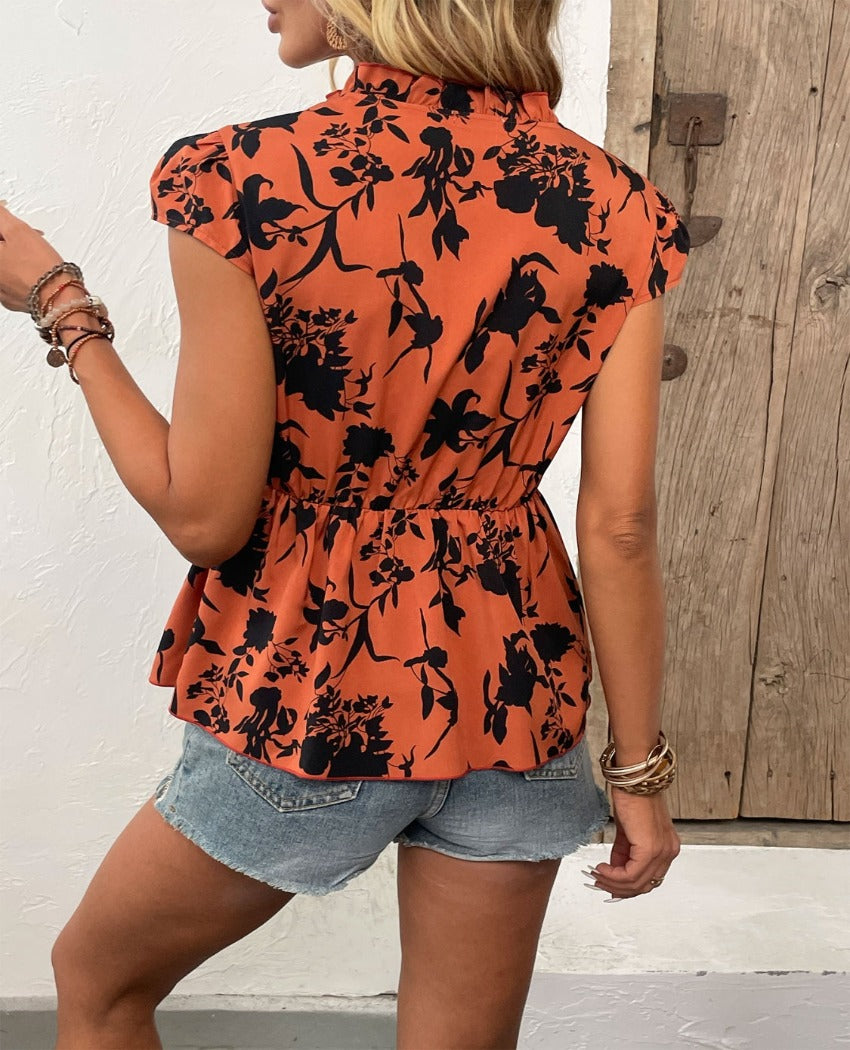 Chic orange floral tie-neck blouse with cap sleeves & a cinched waist, perfect for a summer look that's both stylish and comfortable