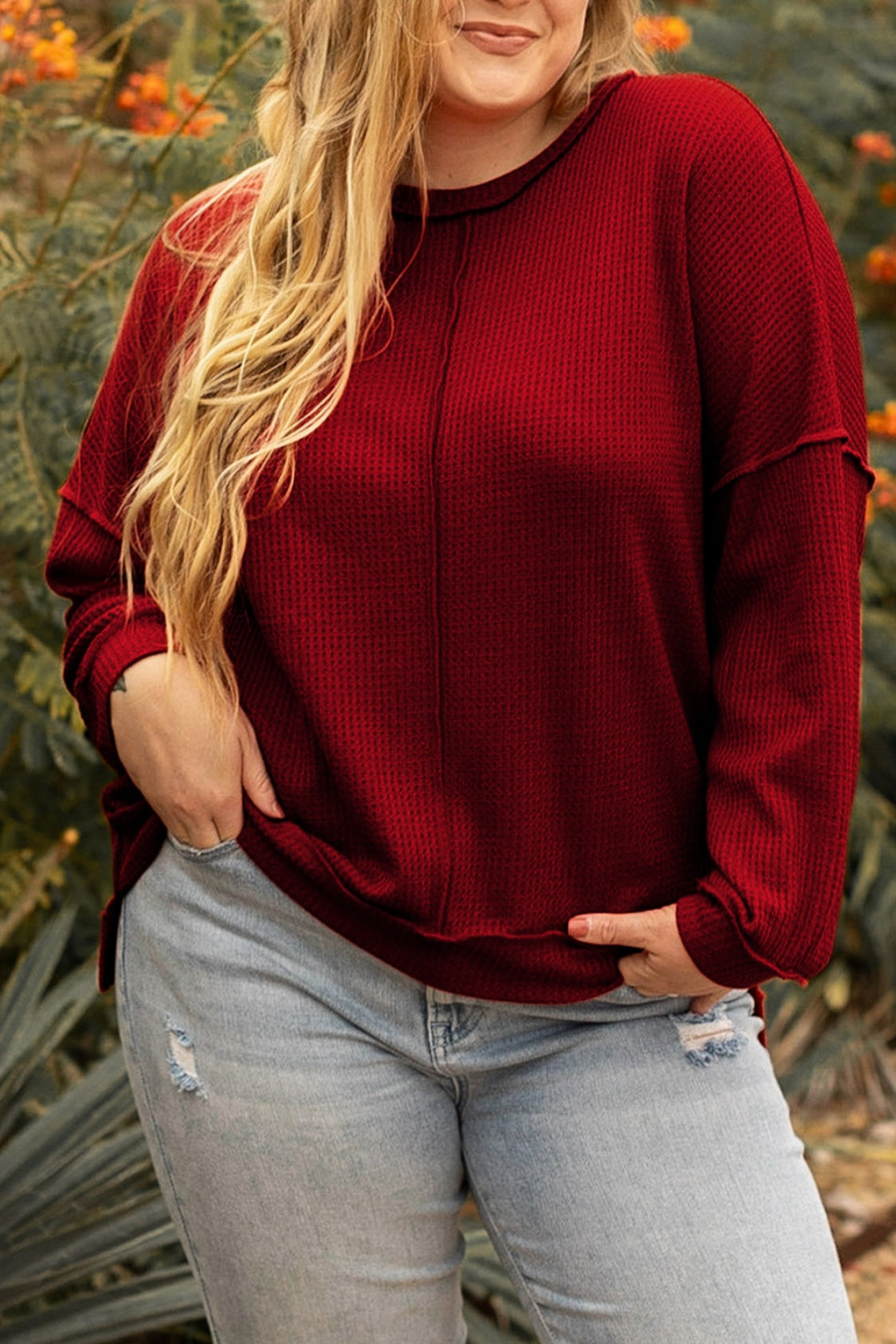 Casual plus-size outfit featuring a burgundy waffle-knit top and distressed jeans