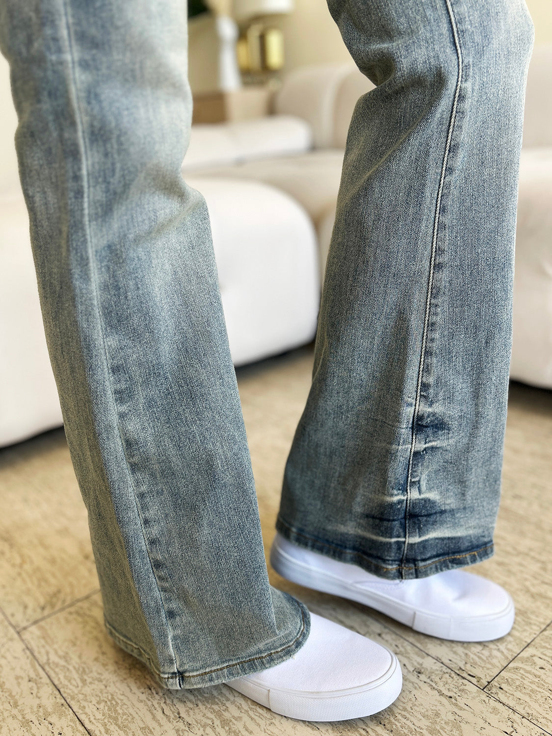 Light wash mid-rise flare jeans with white sneakers.