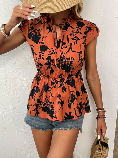 Chic orange floral tie-neck blouse with cap sleeves & a cinched waist, perfect for a summer look that's both stylish and comfortable