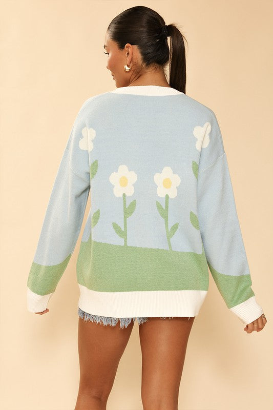 Back view of the Floral Garden Cardigan, showing the wrap-around floral design on a light blue background.