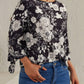 Black and white floral blouse featuring tie sleeves, styled with jeans for a chic look.
