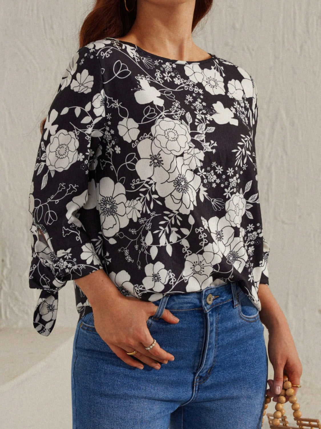 Black and white floral blouse featuring tie sleeves, styled with jeans for a chic look.
