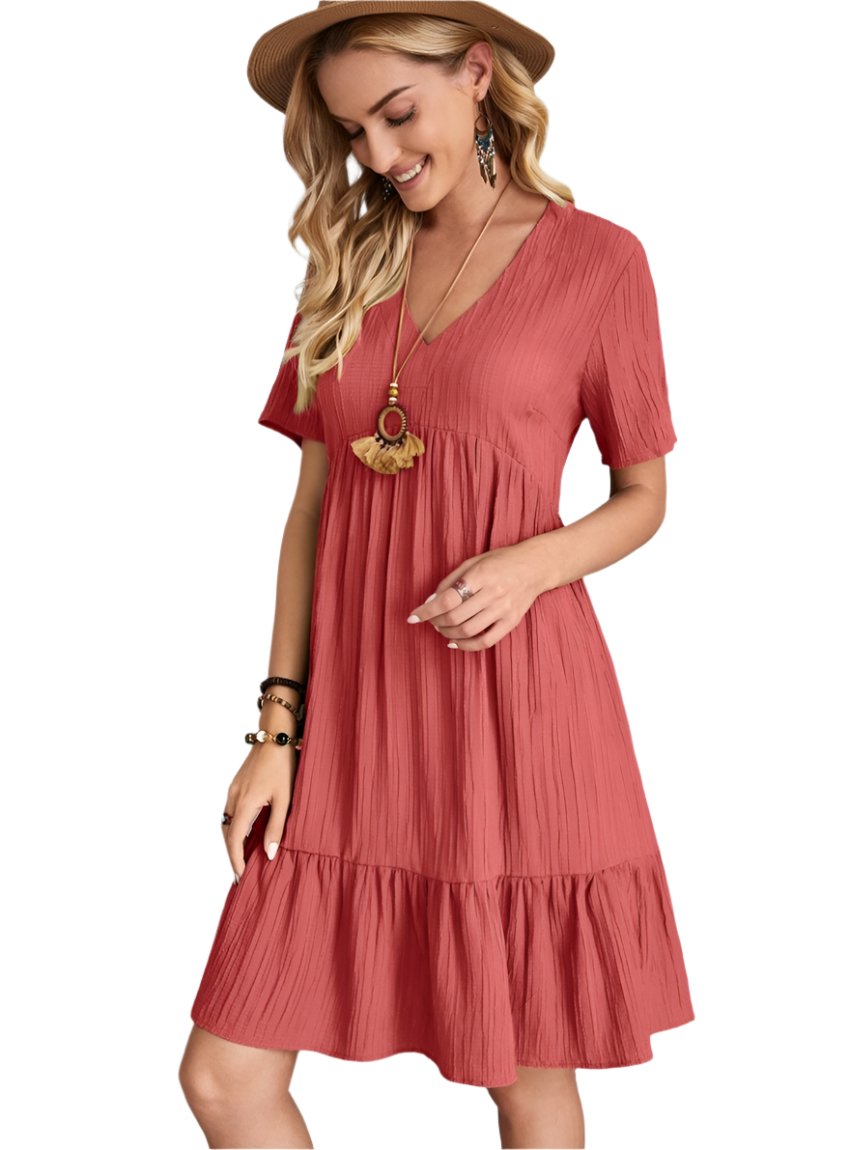 Woman wearing a soft pink babydoll dress with a V-neckline and tiered hem
