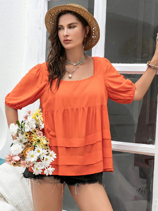 Bright orange peplum top with flowy layers and puff sleeves, styled for a casual summer look
