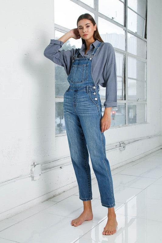 Full-length women’s overalls in medium wash blue denim.
