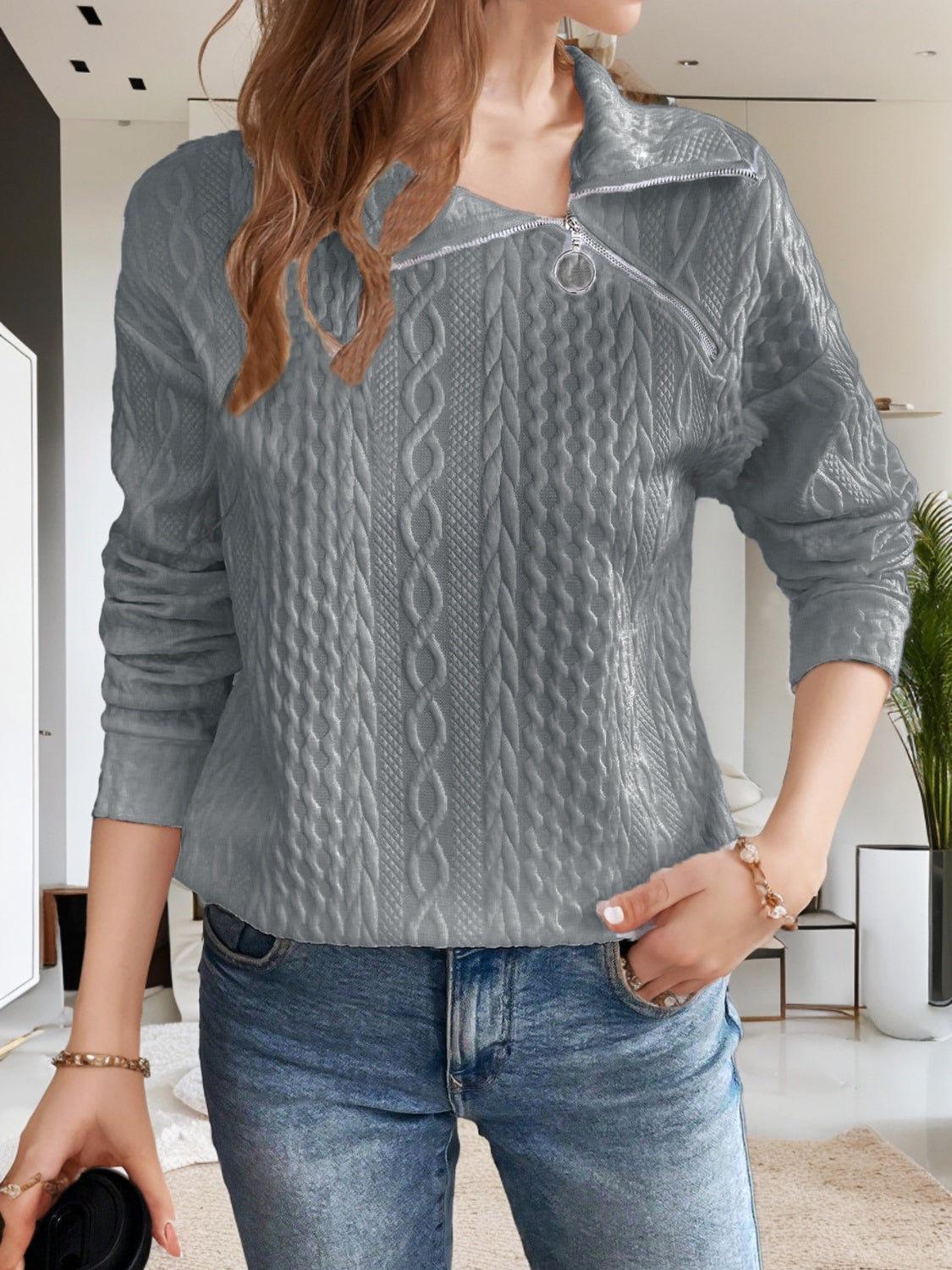 Full-length view of a gray cable knit quarter-zip sweater, great for layering with casual outfits.

