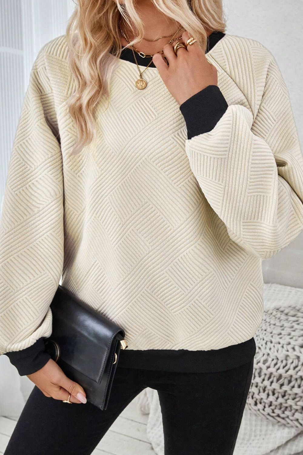 Full-length view of the beige and black pullover sweater, styled for casual wear with jeans or leggings.

