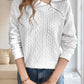 Full-length view of a white cable knit quarter-zip sweater, styled with jeans for a casual chic look.

