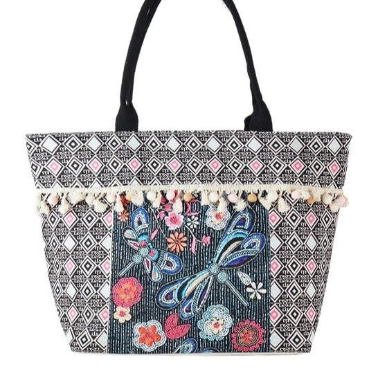 Black and white geometric tote bag with colorful beaded dragonfly design and tassel accents