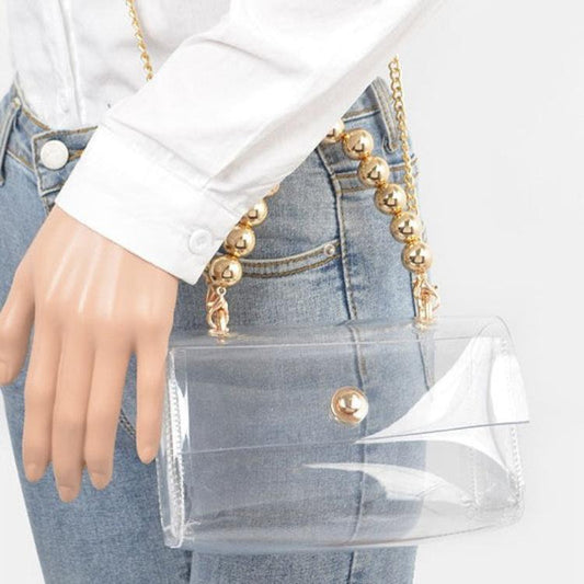 Stylish clear bag featuring a gold beaded handle and chain strap.