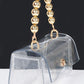 Clear bag with gold beaded handle and removable chain strap, suitable for game day.