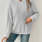 Woman wearing gray ribbed drawstring hoodie with front pocket.
