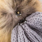 Gray ribbed knit beanie with a faux fur pom, combining comfort and style.
