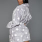 Woman wearing a gray plush robe with white stars, featuring a belt for adjustable comfort.
