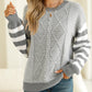 Front view of a gray striped round neck sweater with a relaxed dropped shoulder design.
