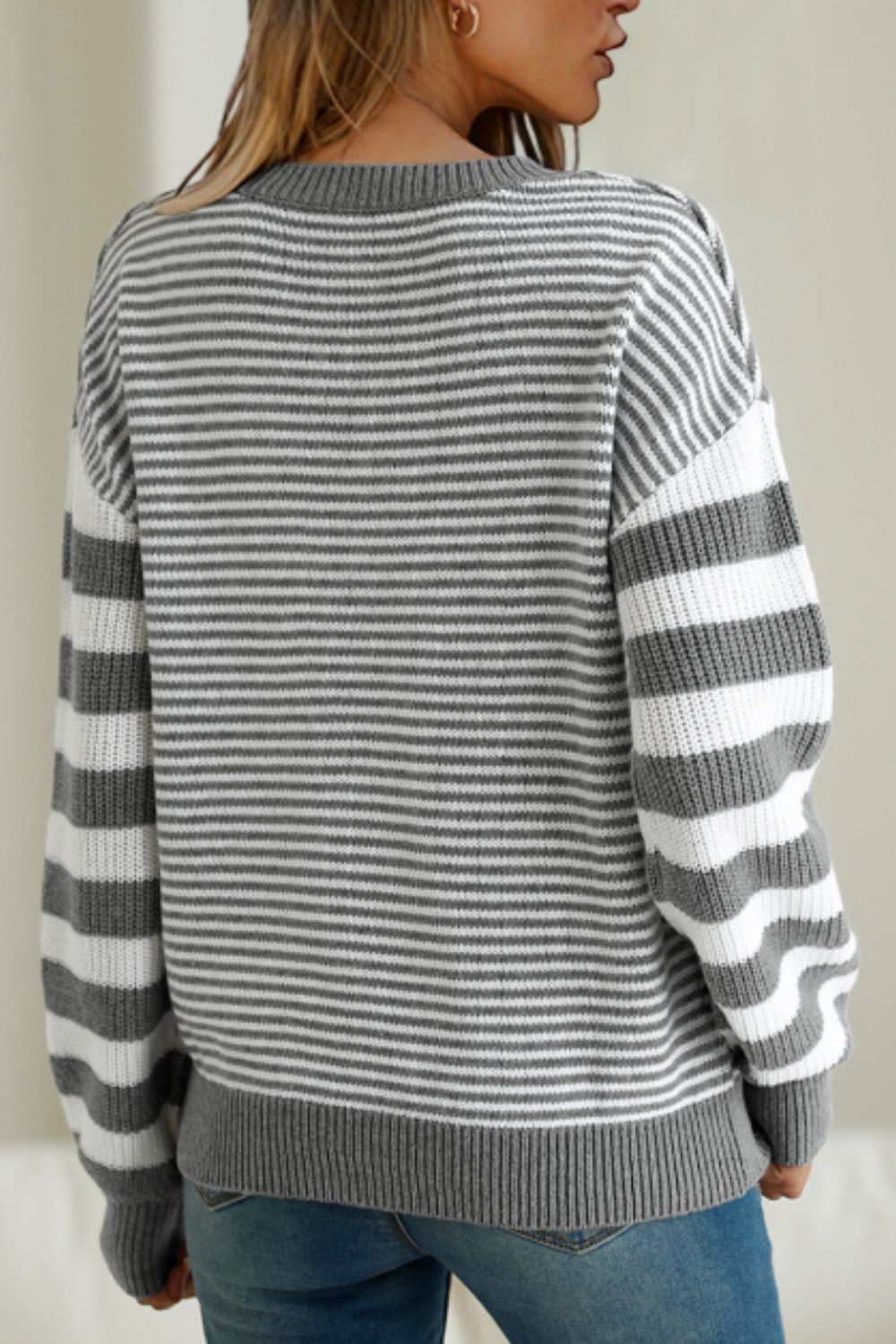 Gray striped sweater with dropped shoulders, perfect for layering in winter.
