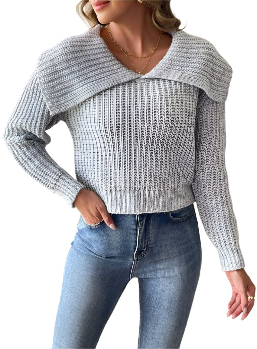 Woman wearing a gray cable-knit wide collar sweater, paired with jeans.
