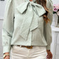 Green gingham puff sleeve blouse with a bow tie, styled for work or casual wear.
