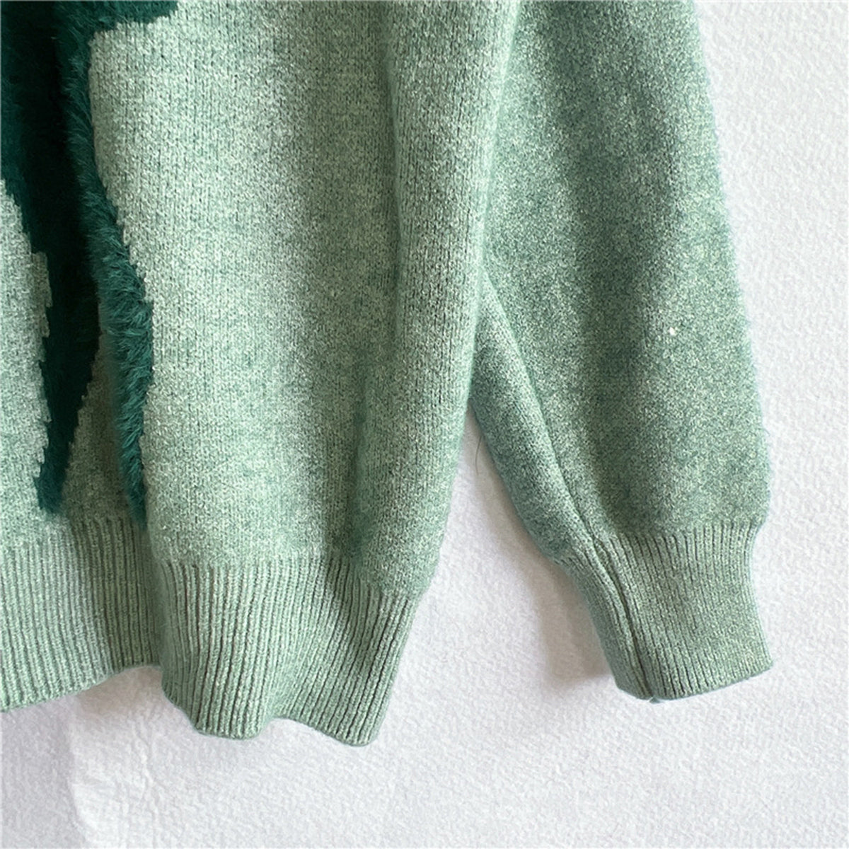 Detailed knit pattern of the green reindeer sweater with a playful holiday reindeer and snowflake motif.

