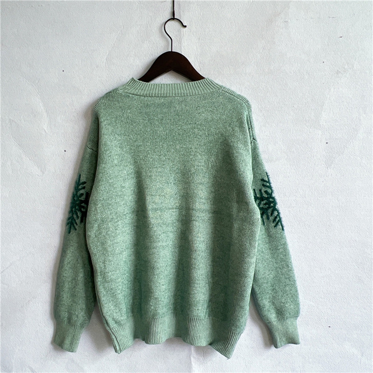 Back view of the green reindeer knit sweater, highlighting the relaxed fit and holiday-themed design.

