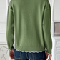 Soft knit green sweater with scalloped trim, styled for casual wear.
