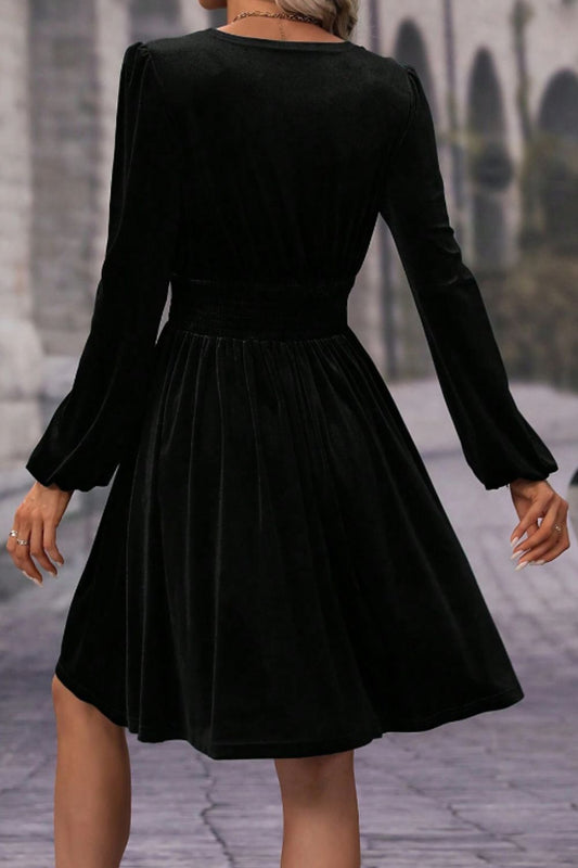 Elegant black wrap dress in velvet fabric, ideal for formal occasions.
